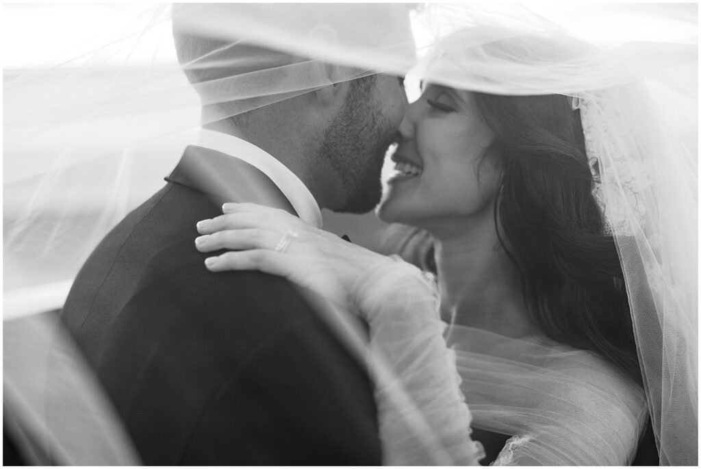 Romantic black and white picture of bride and groom on their wedding day under a veil